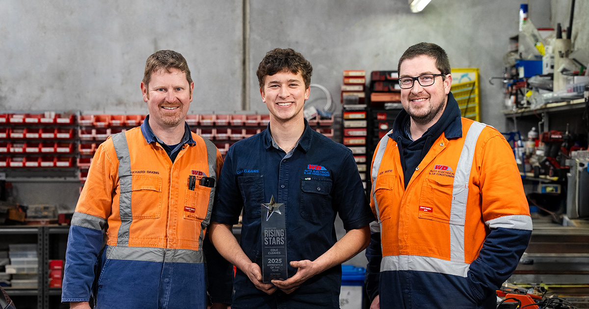 Three people in orange workwear stand in workshop, celebrating Cole Cleaves, 2025 Capricorn Rising Stars VIC/TAS Winner.