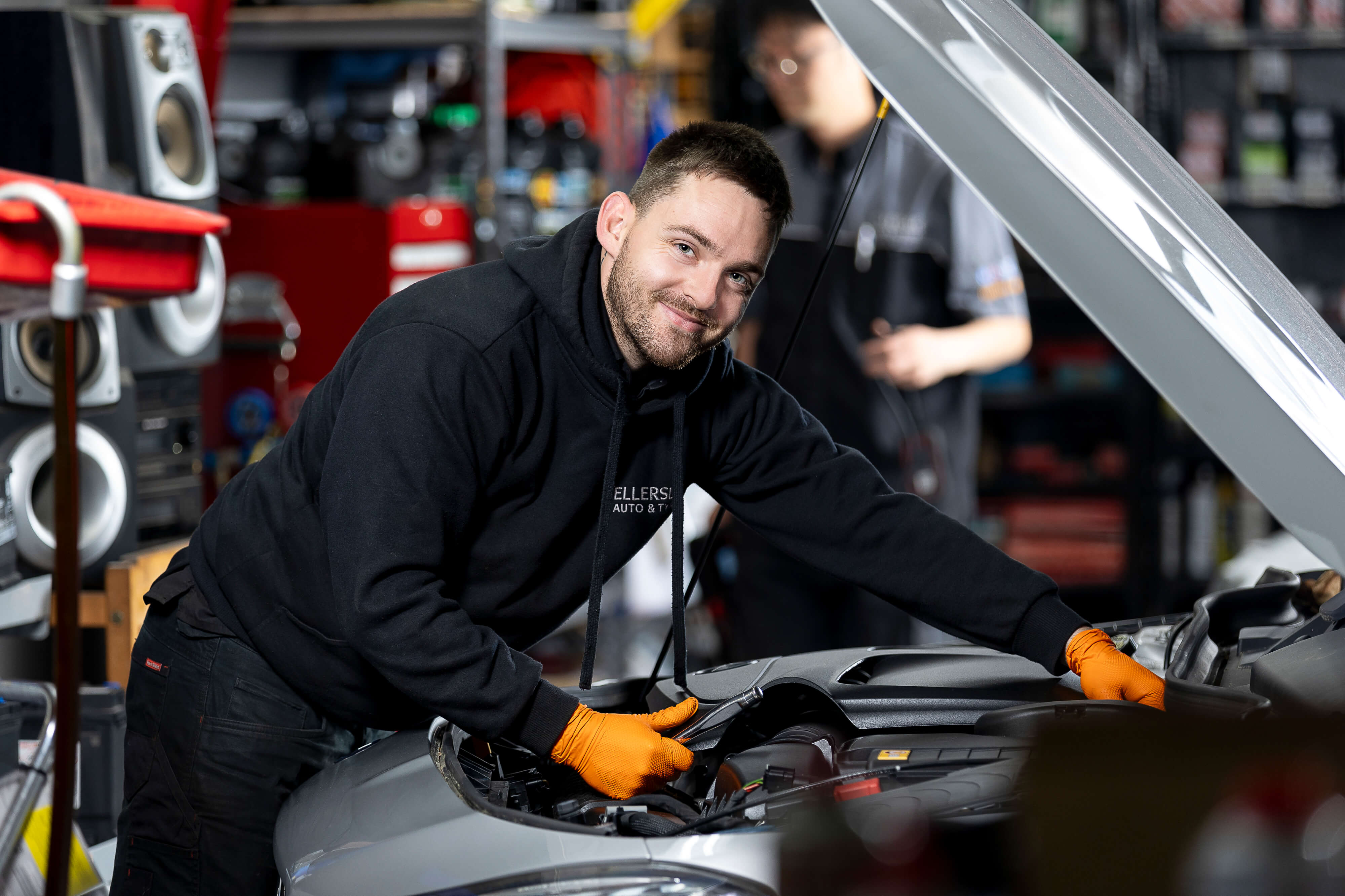 Mechanic leaning over engine smiling at camera
