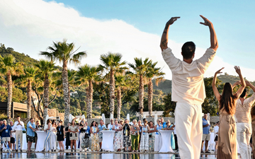 Participants performing yoga poses on the beach, with a scenic ocean view during a conference event.